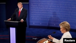 FILE - Republican presidential nominee Donald Trump listens as Democratic presidential nominee Hillary Clinton speaks during their third and final 2016 presidential campaign debate at UNLV in Las Vegas, Oct. 19, 2016. 