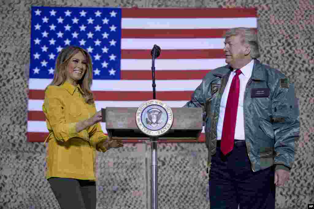 La primera dama Melania Trump, a la izquierda, y el presidente Donald Trump permanecen juntos en el escenario durante un mitin en la base aérea Al Asad, Irak.