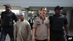 Azim Aghajani, an Iranian citizen, second right, and Nigerian Usman Abbas Jega, second left charged with orchestrating an illegal arms shipment into Nigeria are escorted at the Federal Hight Court in Lagos, Nigeria.