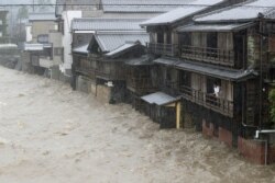 Men watch the Isuzu River, swollen because of heavy rain caused by Typhoon Hagibis in Ise, central Japan, in this photo taken by Kyodo, Oct. 12, 2019.