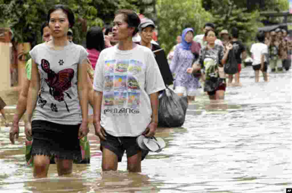 Indonesian women wade through a flooded street in Tangerang in the outskirt of Jakarta, Indonesia, Wednesday, Oct. 27, 2010.