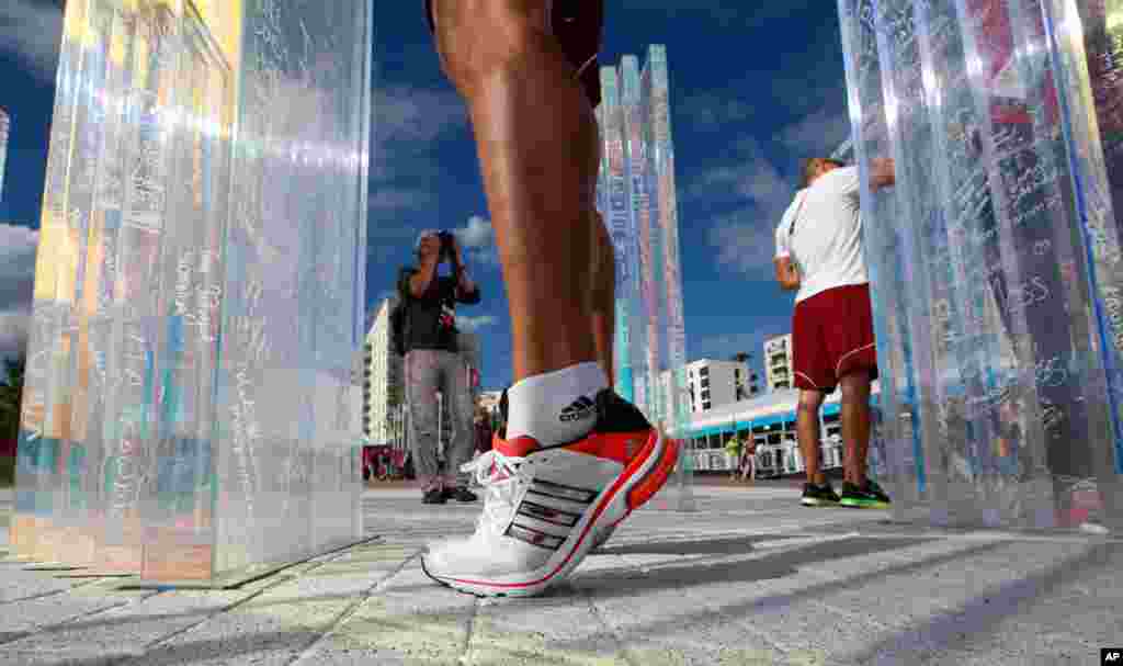 Balazs Baji, an athlete from Hungary, stands on his tiptoes to write on the Olympic truce wall at the Athletes' Village in the Olympic Park.