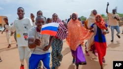 FILE - Supporters of Niger's ruling junta hold a Russian flag in Niamey, Niger, Sunday, Aug. 6, 2023.