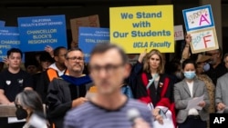 FILE - University of California, Los Angeles faculty and staff members hold up signs during a news conference at UCLA, in Los Angeles, May 9, 2024.