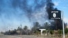 FILE - Smoke raises behind an Islamic State flag flying in Diyala province, Iraq, Nov. 24, 2014.