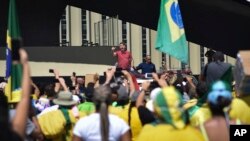 Brazil's President Jair Bolsonaro, center, speaks to supporters during a protest in front the army's headquarters during the Army day, amid the new coronavirus pandemic, in Brasilia, Brazil, April 19, 2020.