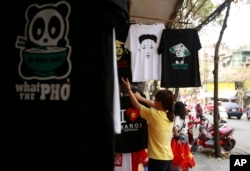 A shopkeeper checks on T-shirts with portraits of U.S. President Donald Trump, and North Korean leader Kim Jong Un, at a shop in Hanoi, Vietnam, Feb. 21, 2019.