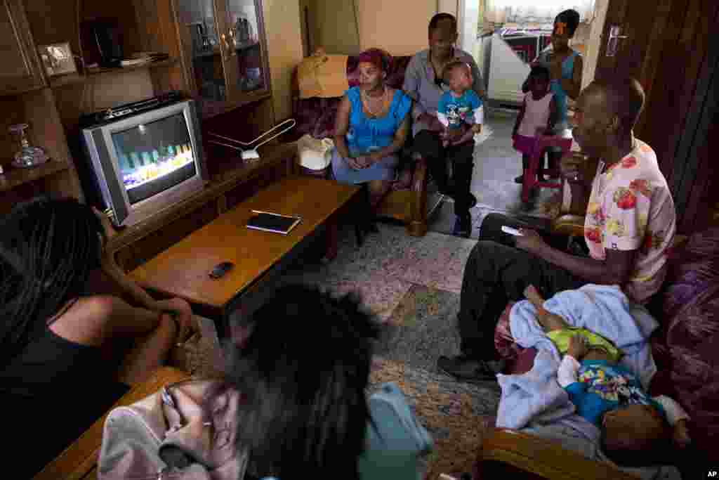 Members of the Mdakane family watch a television in their home showing the funeral service of former South Africa President Nelson Mandela in the Soweto township, Johannesburg.
