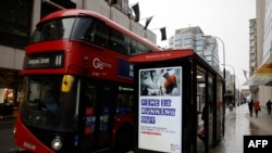 Pedestrians walk past an BTier 2 Coronavirus information displayed on an electronic advertising board at a bus stop in central London on December 14, 2020.