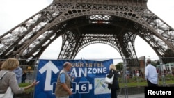 Des touristes marchent autour de la Tour Eiffel, à Paris, France, le 28 juin 2016.