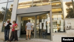 A man checks announcements outside an unemployment bureau in Athens, Greece, August 9, 2012.