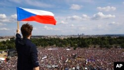 FILE - A man waves the Czech flag as people protest in Prague, Czech Republic, June 23, 2019, calling on Prime Minister Andrej Babis to step down over fraud allegations.