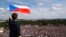 FILE - A man waves the Czech flag as people protest in Prague, Czech Republic, June 23, 2019, calling on Prime Minister Andrej Babis to step down over fraud allegations.