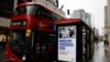 Pedestrians walk past an BTier 2 Coronavirus information displayed on an electronic advertising board at a bus stop in central London on December 14, 2020.