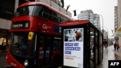 Pedestrians walk past an BTier 2 Coronavirus information displayed on an electronic advertising board at a bus stop in central London on December 14, 2020.