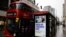Pedestrians walk past an BTier 2 Coronavirus information displayed on an electronic advertising board at a bus stop in central London on December 14, 2020.