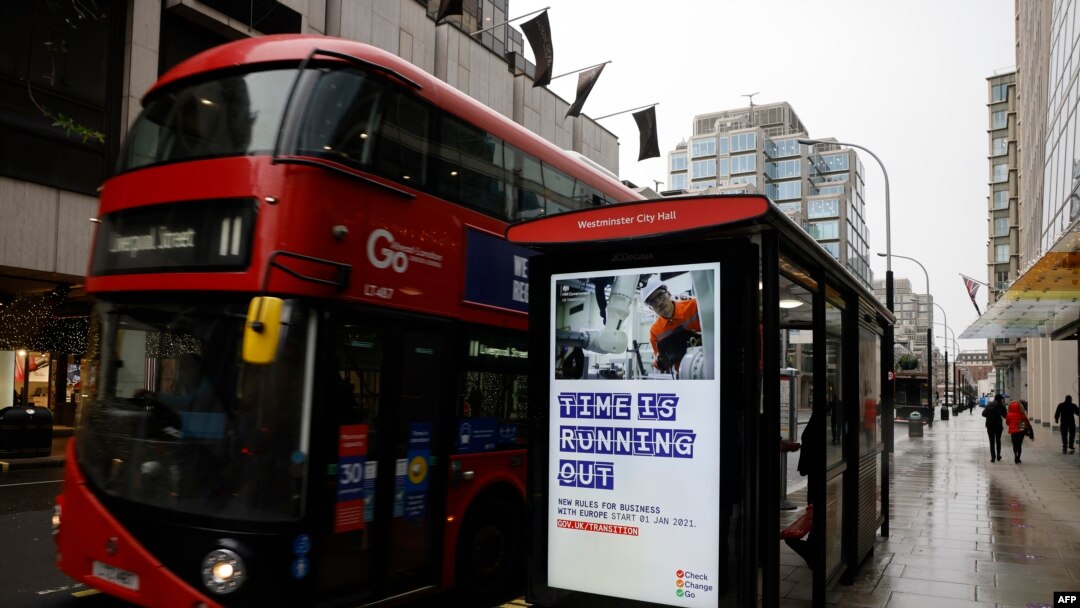 Pedestrians walk past an BTier 2 Coronavirus information displayed on an electronic advertising board at a bus stop in central London on December 14, 2020.