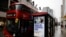 Pedestrians walk past an BTier 2 Coronavirus information displayed on an electronic advertising board at a bus stop in central London on December 14, 2020.