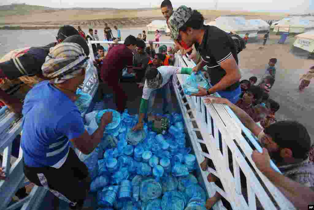 Pengungsi irak berkumpul di sekitar truk makanan untuk mendapatkan hidangan berbuka puasa dalam hari pertama Ramadan di kamp Khazer, di luar kota Irbil, Irak utara (29/6).&nbsp;(AP/Hussein Malla)