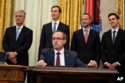 Kosovo Prime Minister Avdullah Hoti, seated, listens as President Donald Trump speaks during a signing ceremony in the Oval Office of the White House, in Washington, Sept. 4, 2020.