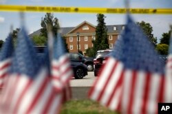 Banderas estadounidenses forman parte de un altar improvisado al borde de un cordón policial frente a un edificio municipal que fue el escenario de un tiroteo, el sábado 1 de junio de 2019, en Virginia Beach, Virginia.