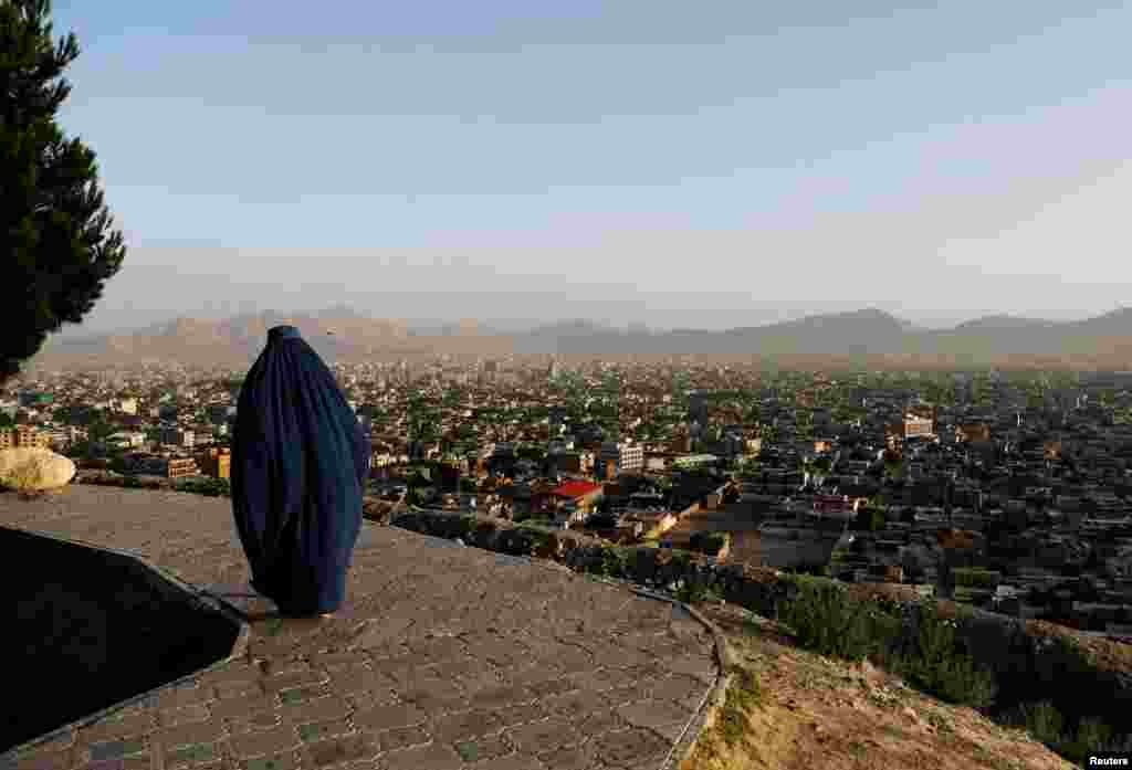 An Afghan woman walks on a hilltop overlooking Kabul.