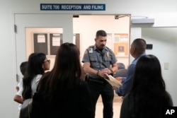 FILE - An officer listens to a question as he directs people to an immigration courtroom, Jan. 10, 2024, in Miami. The number of international migrants who came to Miami-Dade County last year — more than 54,000 people — was the most in the U.S.