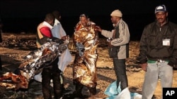 Migrants receive assistance as they arrive on the tiny island of Lampedusa, Italy, early Sunday, May 8, 2011