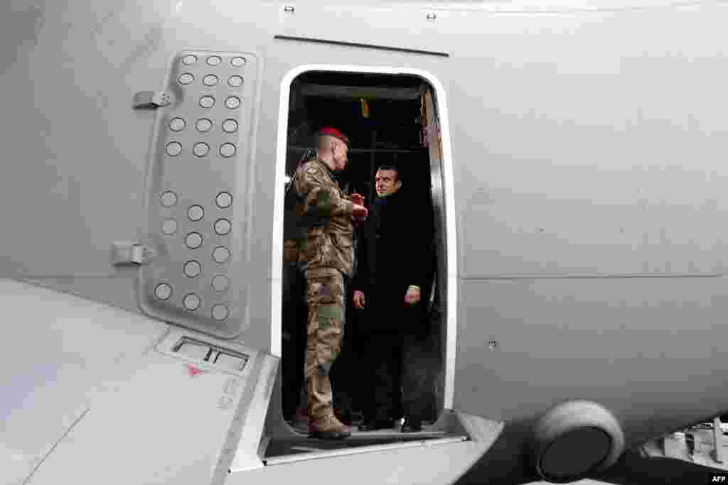 French President Emmanuel Macron (R) appears at the door of a military troop transport aircraft as he meets with infantry paratroopers during a visit to deliver his 2019 New Year&#39;s wishes to the military forces, at the air force base 101 Toulouse-Francazal, near Toulouse, southern France.