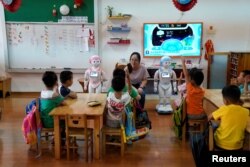 An iPal couple social robots help teach children at a kindergarten in Suzhou, Jiangsu province, China, July 4, 2018. Designed to offer education, care and companionship to children and the elderly, the 3.5-feet tall humanoid robots come in two genders and can tell stories, take photos and deliver educational or promotional content.