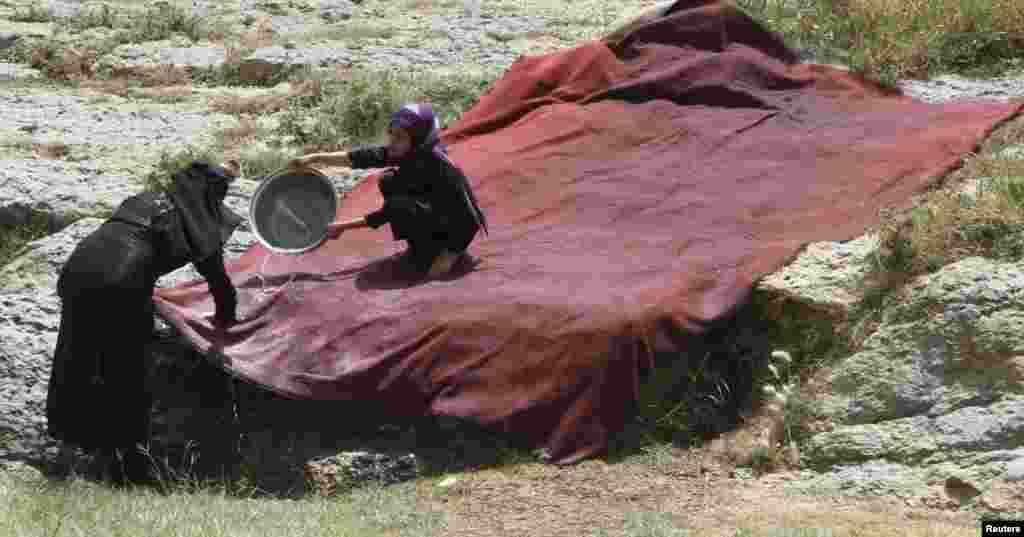 A girl helps her mother wash a large piece of fabric, outside Sana&#39;a, Yemen. 