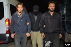 FILE - A masked Turkish special force police officer detains two men during a house raid to arrest suspected members of the Islamic State group, in Adana, on Nov. 10, 2017.