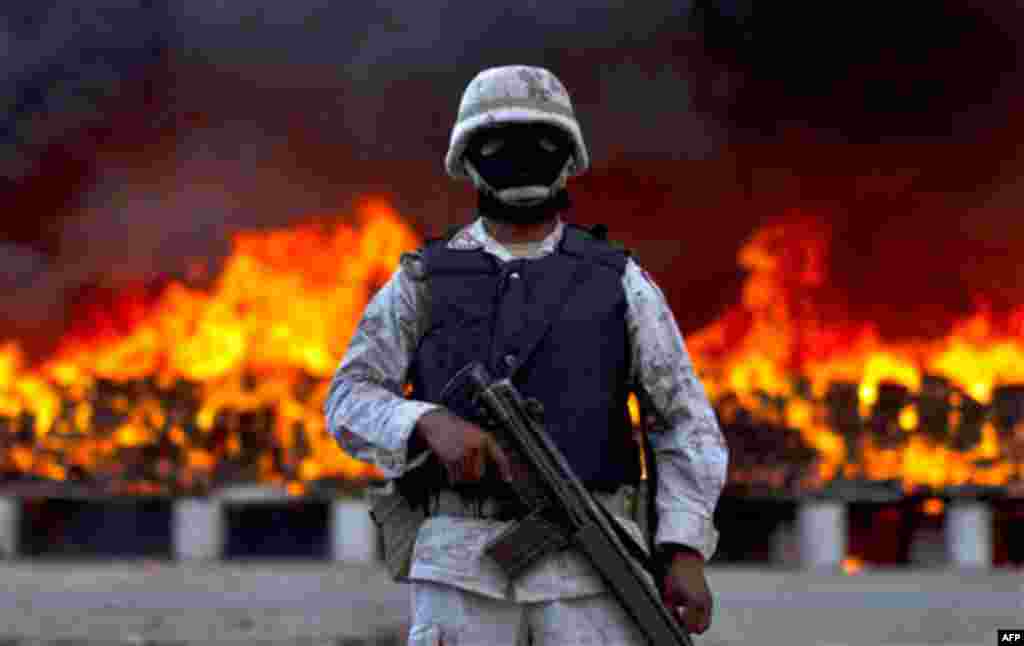 A soldier guards next to packages of marijuana that are being incinerated in Tijuana, Mexico, Wednesday, Oct. 20, 2010. On a conjoined operation with the army, local and state police seized 134 tons of U.S.-bound marijuana Monday, by far the biggest drug 