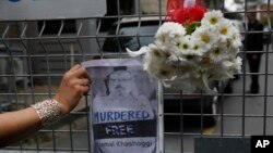 Sahar Zeki, an activist and a friend of slain Saudi writer Jamal Khashoggi, attaches a picture of him and a bouquet of flowers on the barriers blocking the road leading to Saudi Arabia's consulate in Istanbul, Oct. 23, 2018.