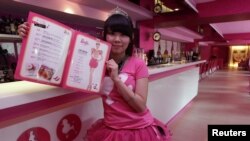 Seorang pelayan di kafe bertema Barbie berpose dengan buku menu. (Reuters/Pichi Chuang)