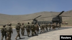 Tentara NATO berbaris memasuki helikopter Chinook menyusul upacara serah terima keamanan di akademi militer di luar Kabul (18/6). 