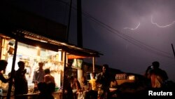 FILE - People gather at a local shop during a thunderstorm in the outskirts of Dhaka, Banglaesh. The South Asian country has seen a near-record number of deaths in 2016 from a phenomenon that appears to be worsening with climate change: lightning strikes.