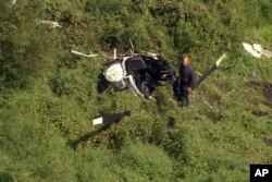In this image from video provided by NBC10 Philadelphia, a first responder examines the wreckage of a helicopter in Lumberton, N.J., Sept. 8, 2017.