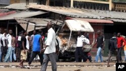 Residents look at a vehicle of FDS - troops loyal to incumbent president Laurent Gbagbo - burned in the Abobo district of Abidjan, 12 Jan 2011