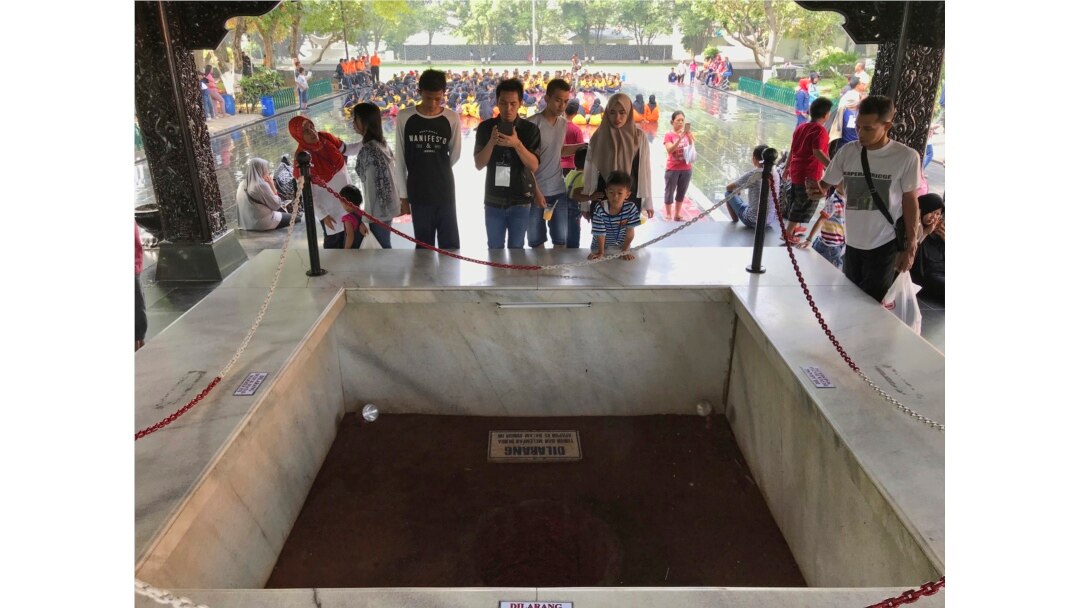 Para pengunjung melihat lubang sumur tempat jenazah enam jenderal dan satu perwira muda Angkatan Darat dikubur dalam peristiwa G30S 1965, di Monumen Pancasila Sakti, Jakarta, 15 Oktober 2017. (Foto: AP)