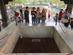Para pengunjung melihat lubang sumur tempat jenazah enam jenderal dan satu perwira muda Angkatan Darat dikubur dalam peristiwa G30S 1965, di Monumen Pancasila Sakti, Jakarta, 15 Oktober 2017. (Foto: AP)