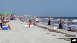 FILE - Vacationers relax on the beach and in the surf at Oak Island, N.C. — an area where two shark attacks have occurred in the last two weeks.