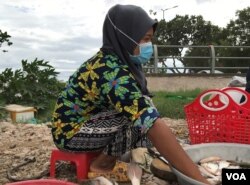 អ្នកស្រី ច្វា រីយ៉ា​ កំពុង​អង្គុយលក់​ត្រី​នៅ​ក្បែរ​ផ្លូវ​ជិត​មាត់​ទន្លេ​ក្នុង​សង្កាត់ជ្រោយ​ចង្វារ រាធានី​ភ្នំពេញ នៅ​ថ្ងៃ​ទី​២២ ខែ​ឧសភា ឆ្នាំ​២០២១។​ (កាន់ វិច្ឆិកា/វីអូអេ)