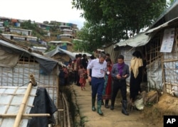 International Committee of the Red Cross President Peter Maurer, foreground left, visits a Rohingya refugee camp in Cox's Bazar, Bangladesh, July 1, 2018.