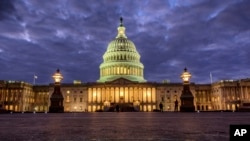 FILE - In this Jan. 21, 2018 file photo, lights shine inside the U.S. Capitol Building as night falls in Washington. 