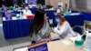 FILE - Tiffany Husak, left, a nursing student at the Community College of Allegheny County, receives her first dose of the Moderna COVID-19 vaccine, during a vaccination clinic in Pittsburgh, Jan. 28, 2021. 