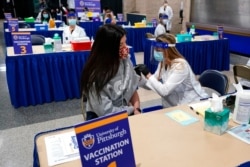 FILE - Tiffany Husak, left, a nursing student at the Community College of Allegheny County, receives her first dose of the Moderna COVID-19 vaccine, during a vaccination clinic in Pittsburgh, Jan. 28, 2021.