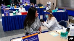 FILE - Tiffany Husak, left, a nursing student at the Community College of Allegheny County, receives her first dose of the Moderna COVID-19 vaccine, during a vaccination clinic in Pittsburgh, Jan. 28, 2021. 