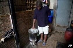 FILE - A Kenyan uses charcoal to heat water to take bath as there was no electricity Saturday, Aug. 26 2023.