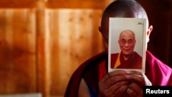 FILE - A monk holds a picture of Tibetan spiritual leader Dalai Lama inside of his room at Labrang Monastery in Xiahe county, Gansu Province.